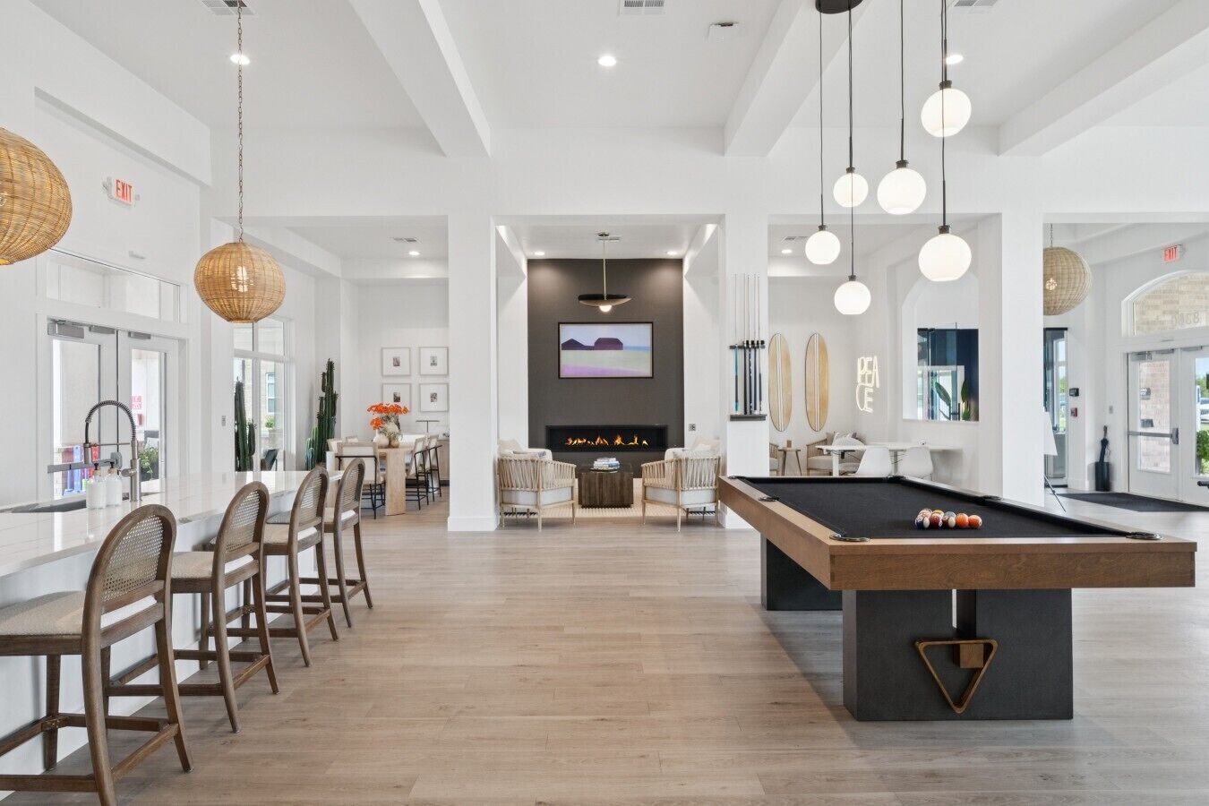 Une pièce spacieuse comprenant une table de billard, un coin repas et un salon avec une cheminée.