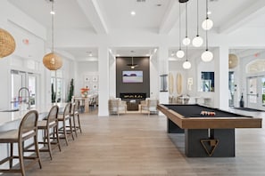 A spacious room with a pool table, dining area, and a living room with a fireplace.