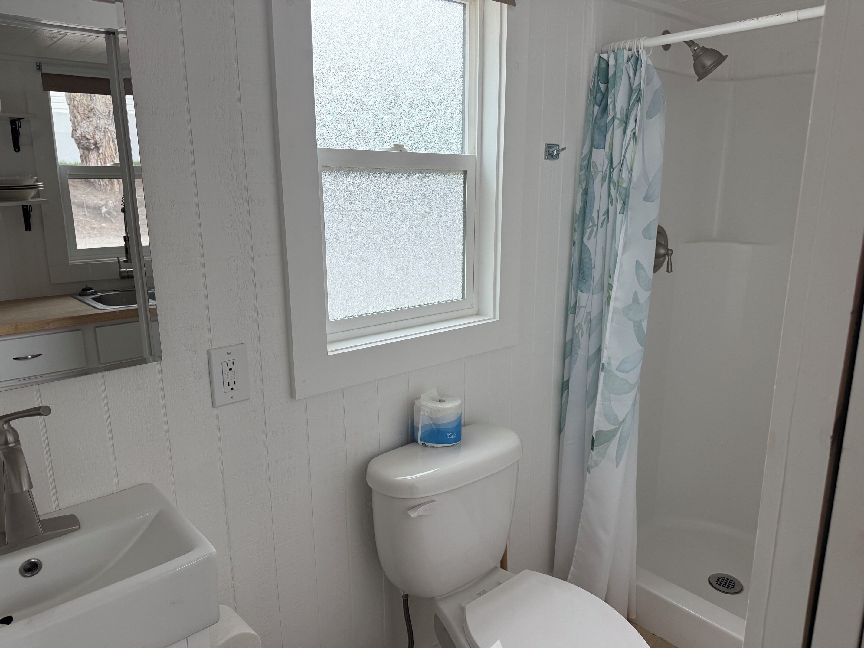 A bathroom with a toilet, sink, and shower.