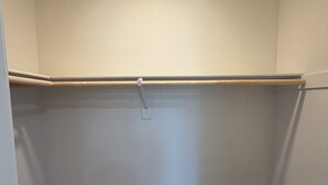 A small, empty room with white walls, a brown carpet, and a wooden closet rod. - Verano Gateway (Cathedral City)