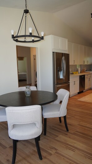 Een moderne keuken met witte kasten, een roestvrijstalen koelkast en een ronde eettafel met twee stoelen.