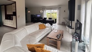Ein Wohnzimmer mit Sofa, Couchtisch, Fernseher und Küchenzeile.