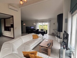Ein Wohnzimmer mit Sofa, Couchtisch, Fernseher und Küchenzeile.