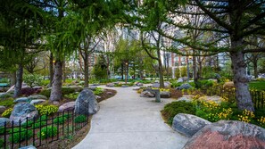 A pathway lined with large rocks and trees, leading to a building with a glass facade. -  3BR Penthouse Downtown & Lakeview by CN Tower- Pool, Gym, Parking (Toronto)