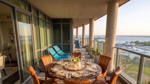 Ein Balkon mit rundem Esstisch, Stühlen und Blumentöpfen.