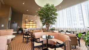 Et moderne loungeområde med et centralt siddeområde, et stort træ og en bar med hylder.