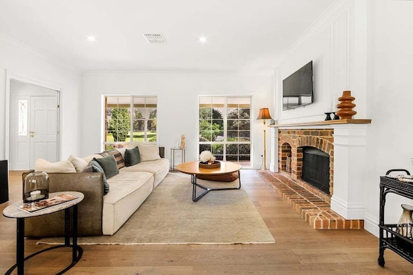 A living room with a sofa, coffee table, fireplace, and large windows.