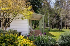 A house with a covered porch, surrounded by lush greenery and trees.