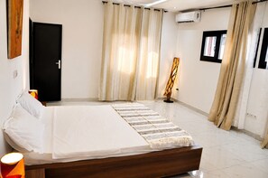 Ein Schlafzimmer mit Bett, Vorhängen, einer Stehlampe und einer Klimaanlage.