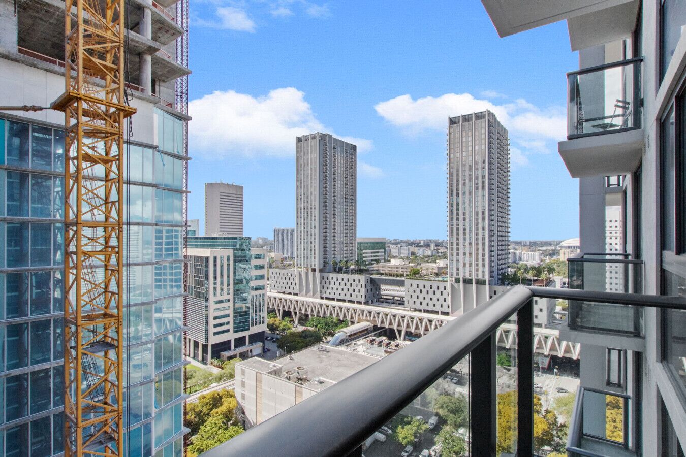 A high-rise building with a construction crane, modern architecture, and a view of surrounding high-rise buildings.