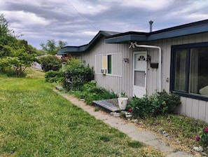 A single-story house with a front door, a small porch, and a pathway leading to the entrance.