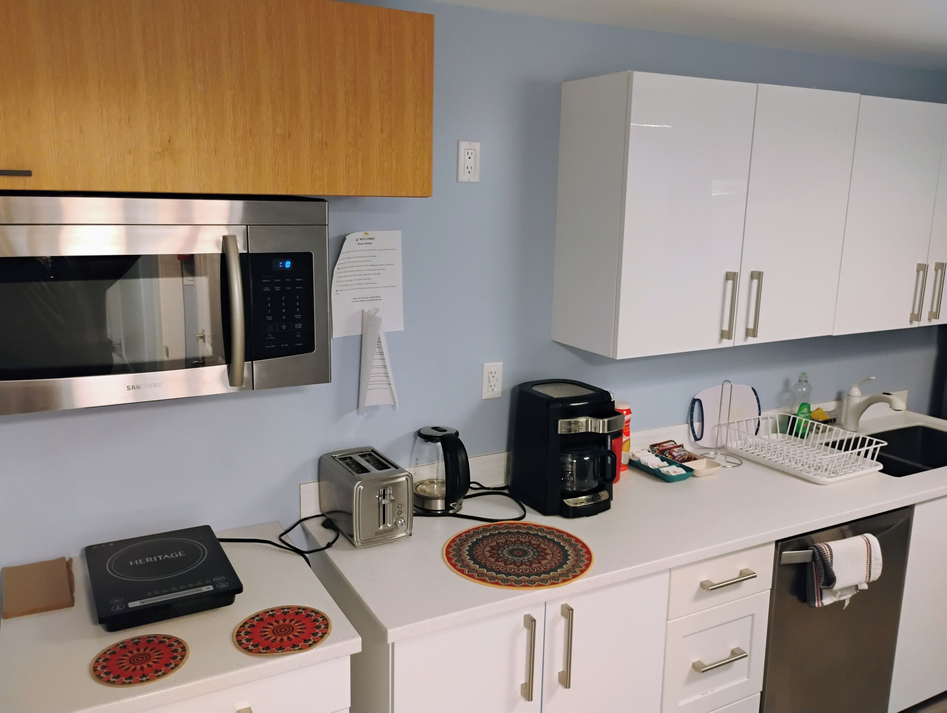 Cozinha moderna com eletrodomésticos de aço inoxidável, armários brancos e pratos decorativos.