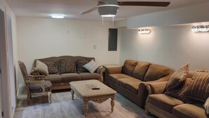 Un salon avec deux canapés, une table basse, un fauteuil et un ventilateur de plafond.