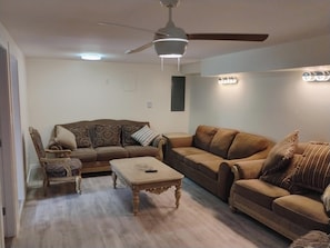 A living room with two sofas, a coffee table, a chair, and a ceiling fan.
