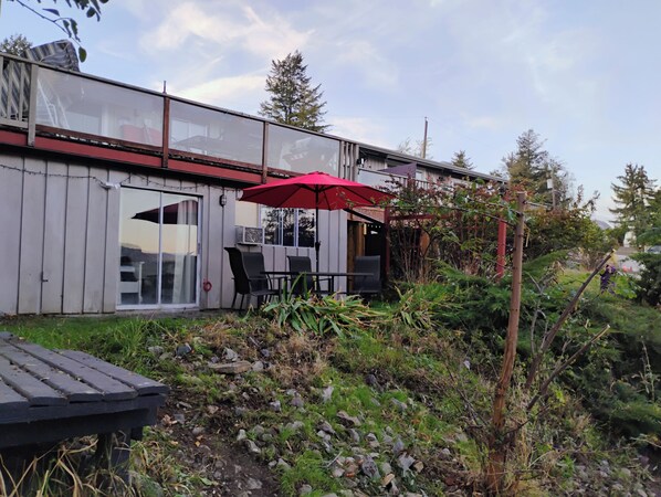 A patio area with a table and chairs, an umbrella, and a wooden deck. - Cozy 2 Bedrooms, Mountain View Private suite (Vernon)