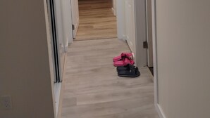 Un couloir étroit mène à une cuisine dotée d’un plancher en bois et d’un four à micro-ondes.