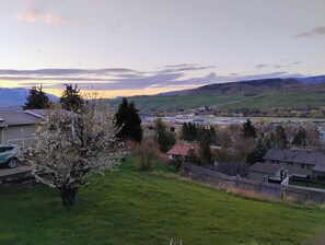 A residential area with houses, a tree in bloom, and a distant view of a town. - Cozy 2 Bedrooms, Mountain View Private suite (Vernon)