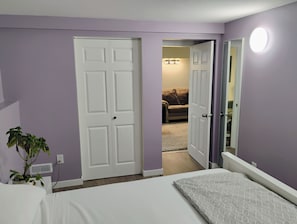 A bedroom with a bed, a potted plant, a door, and a hallway leading to another room. - Cozy 2 Bedrooms, Mountain View Private suite (Vernon)