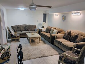 A living room with two sofas, a coffee table, a ceiling fan, and decorative wall lights. - Cozy 2 Bedrooms, Mountain View Private suite (Vernon)