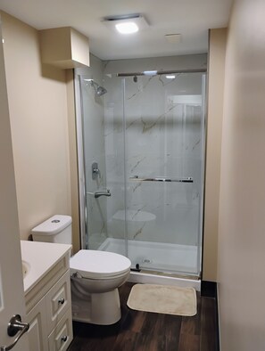 Une salle de bain avec une douche à parois de verre, des toilettes et un lavabo.