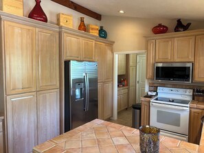A kitchen with wooden cabinets, a stainless steel refrigerator, a microwave, and an oven. - Peaceful 2-bedroom country house nestled on a 26 acre ranch in charming Ramona. (Ramona)
