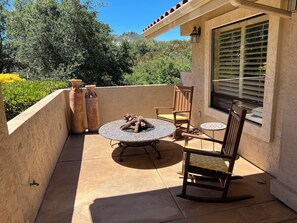 A patio with a round table, two chairs, a fire pit, and two large vases. - Peaceful 2-bedroom country house nestled on a 26 acre ranch in charming Ramona. (Ramona)