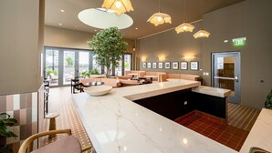 A modern lobby with a marble reception desk, seating areas, pendant lighting, and framed artwork on the walls. - The Crosby #2012 - Luxury 1 Master Bedroom (Miami)