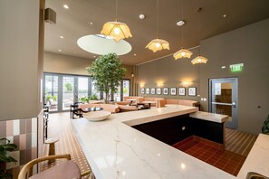 Eine moderne Lobby mit einem Marmor-Empfangstresen, Sitzbereichen, Pendelleuchten und gerahmten Kunstwerken an den Wänden.
