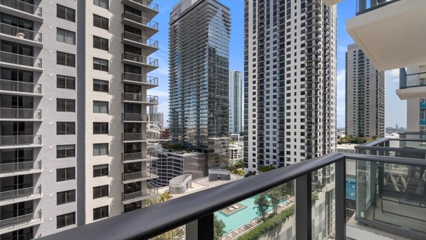 A high-rise building with multiple balconies, a swimming pool, and other residential buildings in the background. - The Crosby #2012 - Luxury 1 Master Bedroom (Miami)