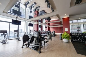 Ein modernes Fitnessstudio mit verschiedenen Trainingsgeräten, großen Fenstern und Blick auf die Stadt.