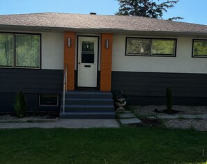 A modern two-story house with a front door, a small porch, and a well-maintained lawn.