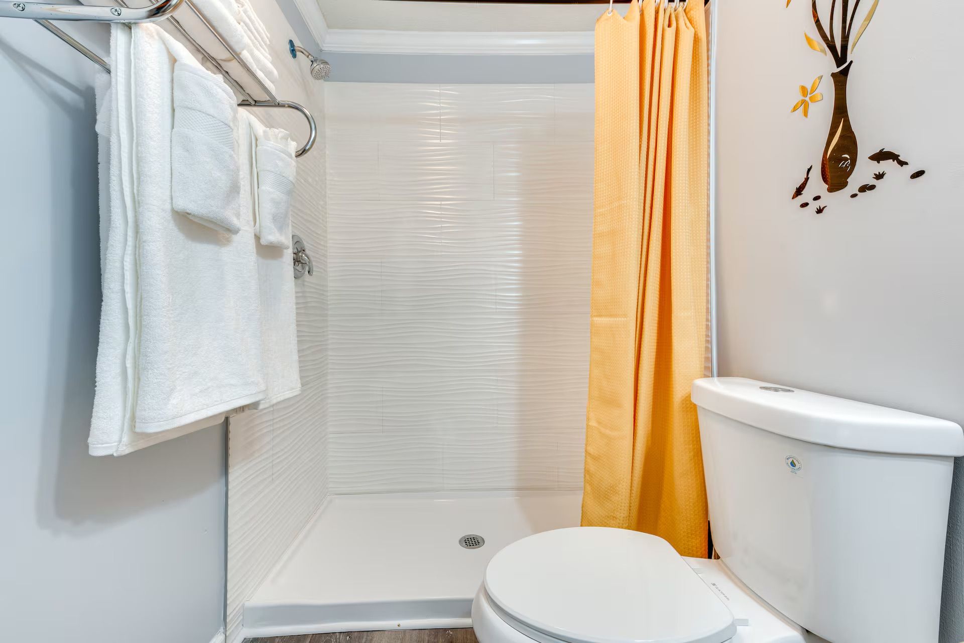Une salle de bain équipée d’une douche, de toilettes et d’un porte-serviettes.