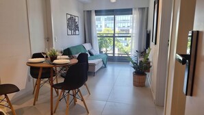 Ein moderner Wohnraum mit Essbereich, einer Couch und einem großen Fenster mit Blick auf Gebäude.