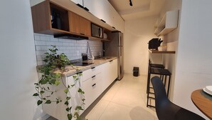 Eine moderne Küche mit weißen Schränken, einer Arbeitsplatte aus Granit und einem Edelstahl-Kühlschrank.
