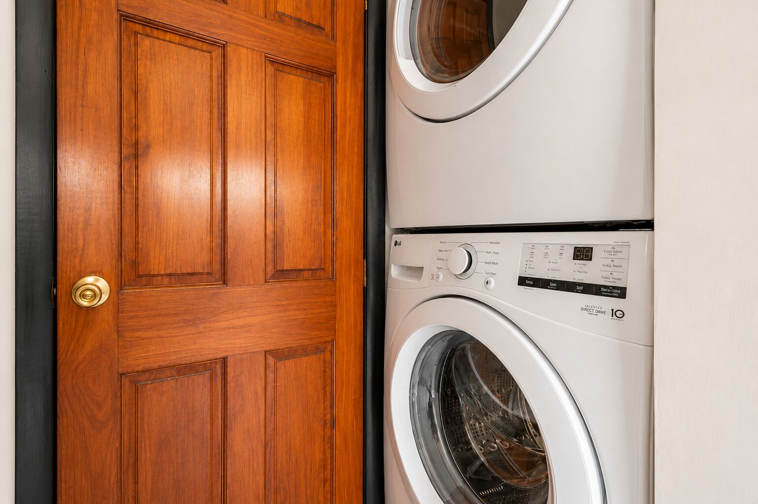 A wooden door and a stacked washer-dryer unit.