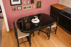 A dining table with a white cup, surrounded by chairs, in a room with a pink wall and a patterned backsplash. - Catskill Creek w/ Deck & Views (Jefferson Heights)