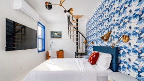 A bedroom with a bed, a desk, a chair, a staircase, and a wall with a floral pattern. - Catskills Getaway Nature Views Fire Pit (Jefferson Heights)