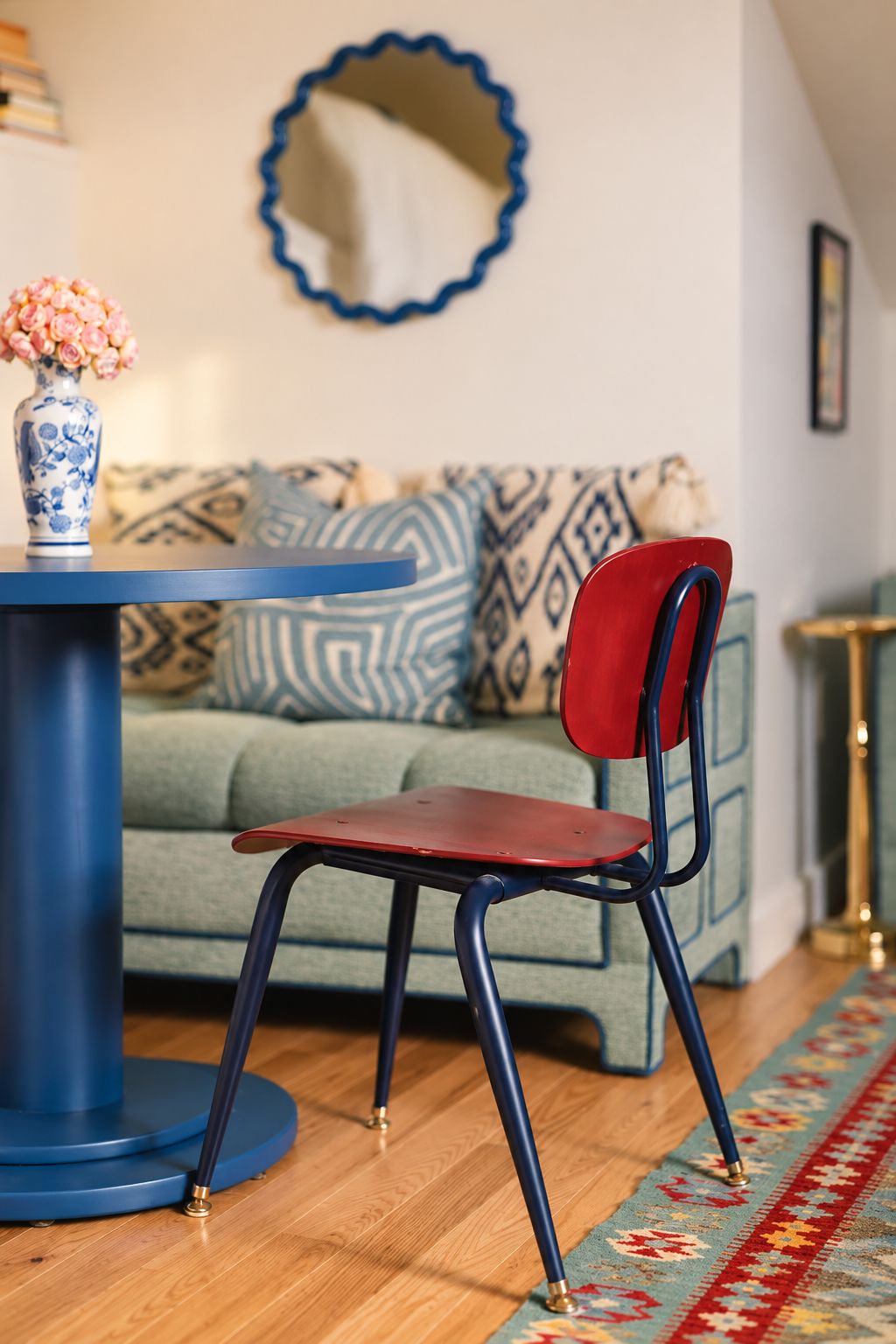 A red chair with a high backrest and a blue table with a vase of flowers.