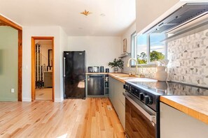 A modern kitchen with a black refrigerator, stainless steel appliances, and a wooden countertop. - Creekview Catskill Lodge w/ Canoes & Mtn Views (Jefferson Heights)