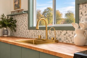 A kitchen with a wooden countertop, a gold faucet, and a tiled backsplash. - Creekview Catskill Lodge & Mountain Views (Jefferson Heights)