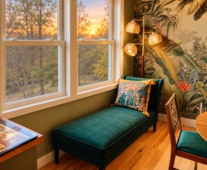A cozy seating area with a bench, a chair, and a table, featuring a view of trees through large windows. - Creekview Catskill Lodge & Mountain Views (Jefferson Heights)