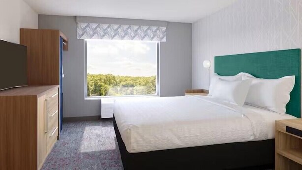 Een hotelkamer met een bed, een televisie, een raam met uitzicht en een kledingkast.
