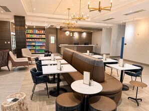 Interior moderno de restaurante com disposição de assentos, área de bar e exposição de bebidas.