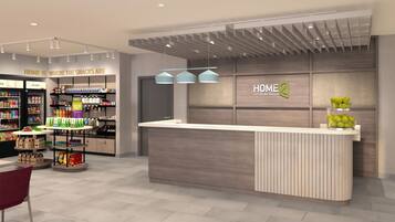 Um saguão de hotel moderno com balcão de recepção, exposição de lanches e uma placa 'HOME 2'.