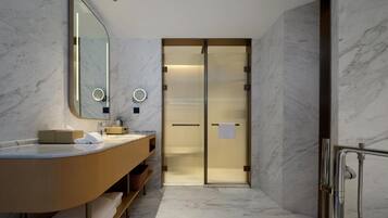 A modern bathroom with a marble floor, a wooden vanity, a large mirror, and a shower area.