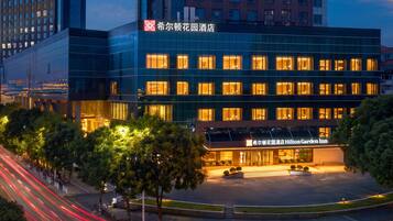 A modern hotel building with a glass facade and illuminated windows.