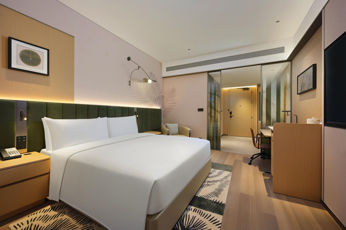 Une chambre d’hôtel avec un grand lit, des tables de chevet, un bureau et une chaise.