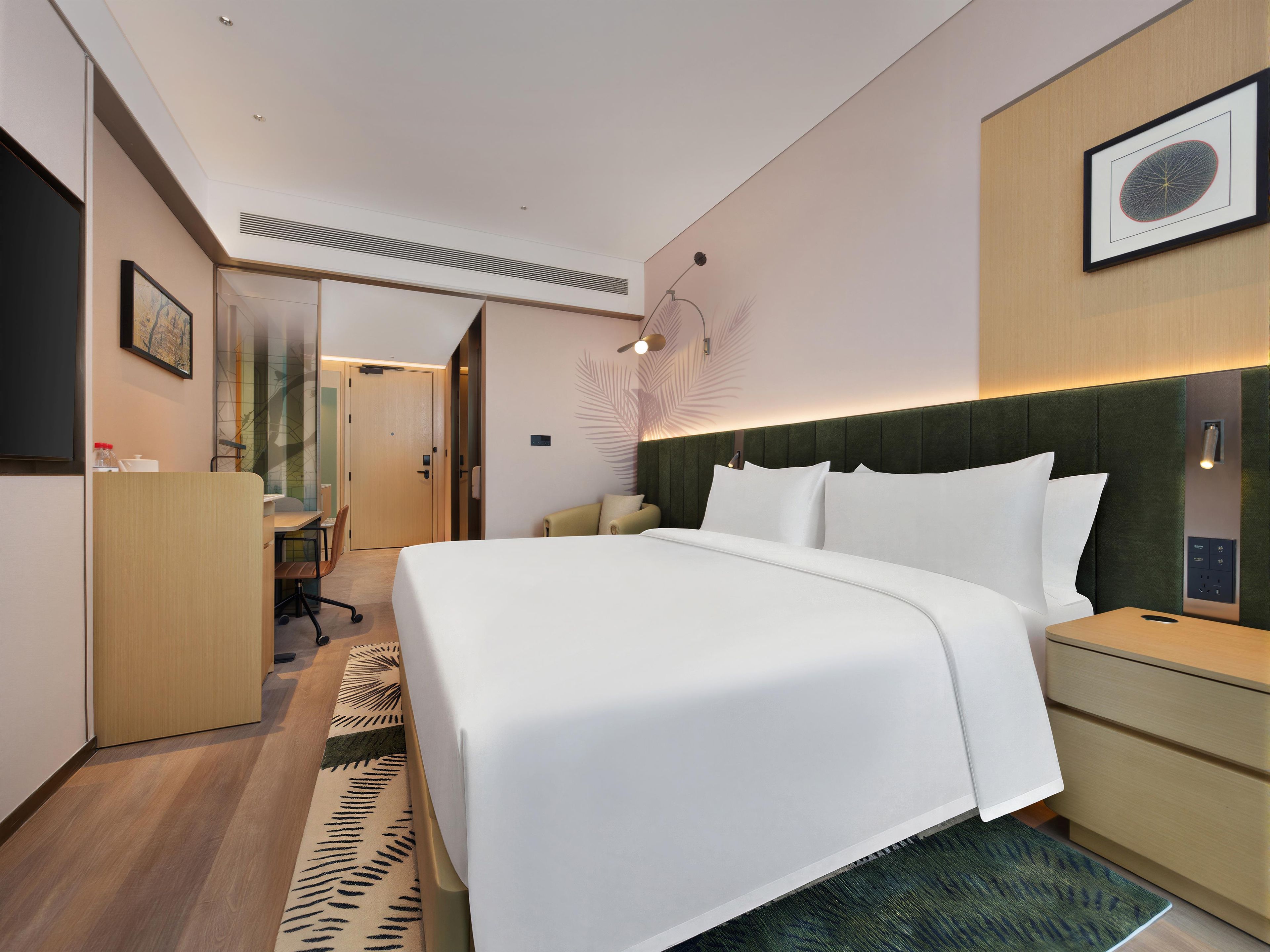 A hotel room with a bed, bedside tables, a desk, and a chair.