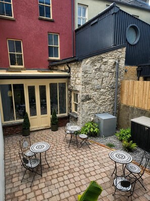 A courtyard with brick flooring, outdoor seating, and a stone wall. - No.60 Sligo (Sligo)