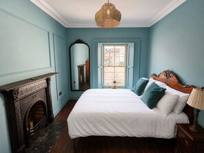 A bedroom with a bed, a mirror, a fireplace, and a window. - No.60 Sligo (Sligo)
